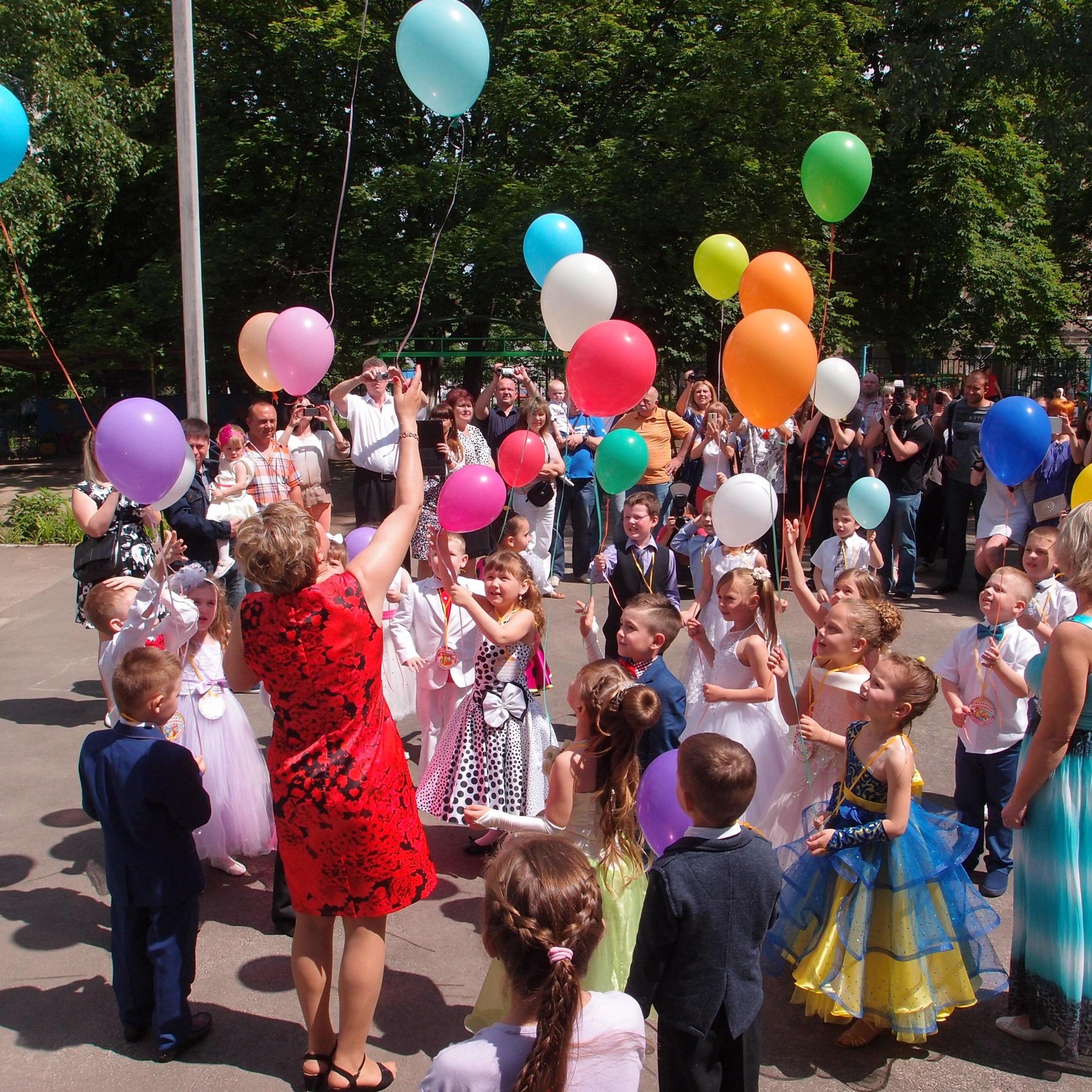 Viele Kinder mit bunten Luftballons an der Schnur